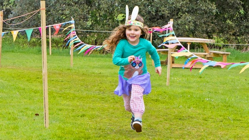 Child running around a race course marked with bunting during Easter activities at Blickling Estate, Norfolk